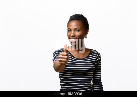 Enthusiastisch motivierten afrikanischen jungen Frau, ein "Daumen hoch" Geste der Anerkennung und Erfolg mit einem strahlenden Lächeln Stockfoto