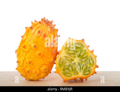 Kiwano Obst, auch bekannt als Cucumis metuliferus, gehörnten Melone, oder Afrikanische gehörnten Gurke sitzen auf Holz Tisch auf Weiß isoliert. Ein ganzes und 1 sli Stockfoto