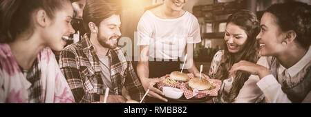 Kellnerin serviert Burger zu Kunden im Restaurant Stockfoto