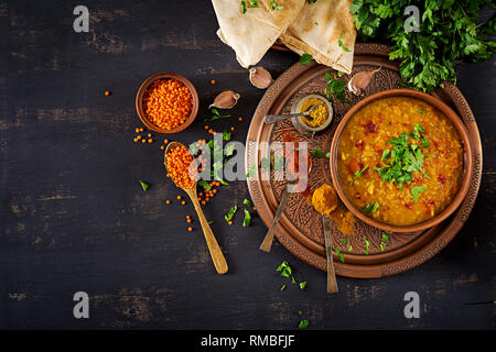 Indisches Dal. Essen. Traditionelle indische Suppe Linsen. Indische Dhal spicy Curry in der Schüssel, Gewürze, Kräuter, rustikale schwarz Holz- Hintergrund. Ansicht von oben. Authenti Stockfoto