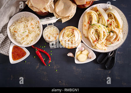 Fermentierter Lebensmittel. Vegetarisches Essen Konzept. Kohl Kimchi, Tomaten, mariniert, Sauerkraut sauer Gläsern über rustikale Küche Tisch. Konserven Konzept Stockfoto