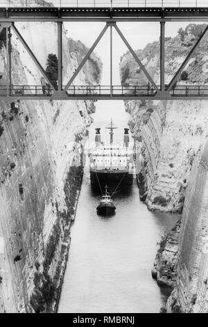 Den Isthmus von Korinth mit einer Eisenbahnbrücke. Es ist 6,5 km lang und wurde 1893 eingeweiht. Der Kanal verbindet das Peleponnese mit dem Festland. Hier ein Passagierschiff ist von einem Piloten durch den Kanal im Jahr 1984 gezogen. Stockfoto