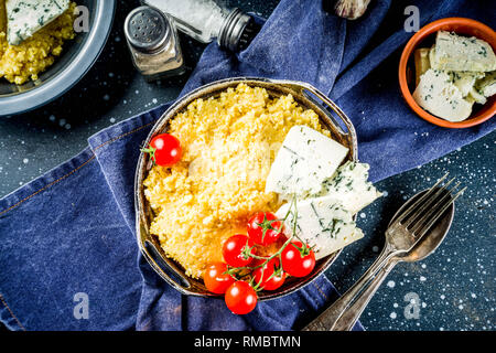 Lombardei italienische Lebensmittel, Polenta Maisbrei mit Tomaten mit Gorgonzola Käse, dunkelblauen Hintergrund Kopie Raum Stockfoto