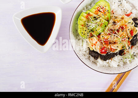 Vegan Salat mit Reis, eingelegte Kimchi Kohl, Avocado, Nori und Sesam auf die Schüssel. Sushi-food-Hybriden Trend. Overhead, Ansicht von oben, flach. Stockfoto