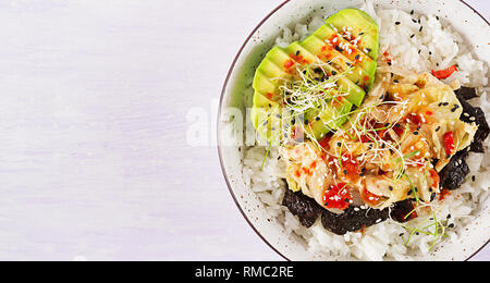 Vegan Salat mit Reis, eingelegte Kimchi Kohl, Avocado, Nori und Sesam auf die Schüssel. Sushi-food-Hybriden Trend. Overhead, Ansicht von oben, flach. Stockfoto