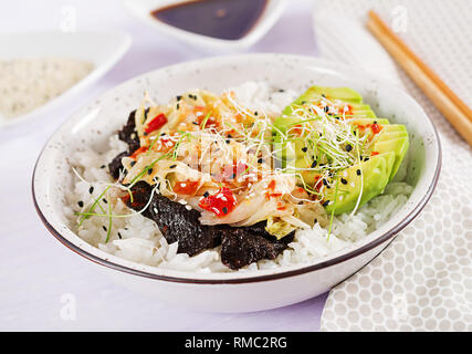 Vegan Salat mit Reis, eingelegte Kimchi Kohl, Avocado, Nori und Sesam auf die Schüssel. Sushi-food-Hybriden Trend. Gemeinkosten Stockfoto