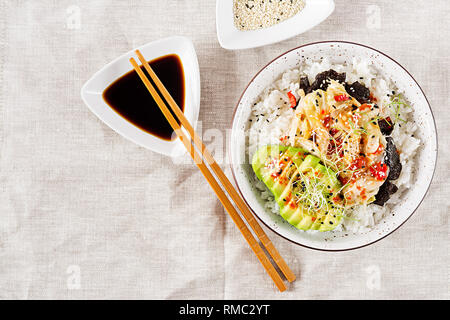 Vegan Salat mit Reis, eingelegte Kimchi Kohl, Avocado, Nori und Sesam auf die Schüssel. Sushi-food-Hybriden Trend. Overhead, Ansicht von oben, flach. Stockfoto