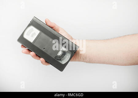 Männliche Hand hält VHS, Video tape, auf dem weißen Hintergrund. Stockfoto