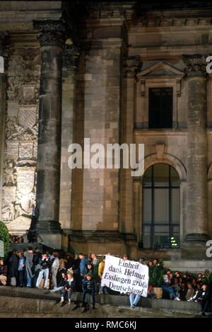 (03.10.1990) Berlin, mit der durch das Banner "Einheit, Helmut - Esslingen grüßt Deutschland', Menschen danke Bundeskanzler Helmut Kohl vor dem Reichstag. Um Mitternacht, die schwarz-rot-goldene Flagge ist vor dem Berliner Reichstag als Symbol der Wiedervereinigung der Bundesrepublik und der DDR erhoben. Stockfoto