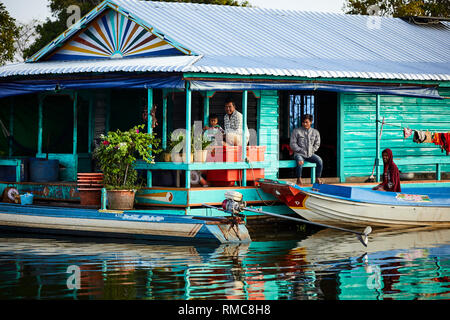 Tonlé Sap See, Kambodscha. 19. Dezember, 2017. Männer und Jungen sitzen außerhalb ihrer Floating House mit Booten vor. Foto: Bryan Watt Stockfoto