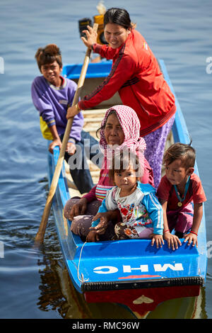 Tonlé Sap See, Kambodscha. 19. Dezember, 2017. Frauen und Kinder in ihre figerglass roat, während eine andere Frau steht und Zeilen. Foto: BryanWatt Stockfoto