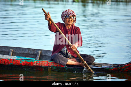 Tonlé Sap See, Kambodscha. 19. Dezember, 2017. Eine alte Dame tragen Brillen Zeilen ihr hölzernes Boot in ein schwimmendes Dorf auf Tonlé Sap See. Stockfoto