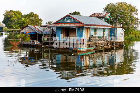 Tonlé Sap See, Kambodscha. 19. Dezember, 2017. Farbenfrohe floating House mit Bäumen hinter und ein hölzernes Boot vor. Foto: Bryan Watt Stockfoto