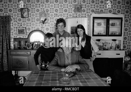 1970s Irisches Familienportrait von drei Generationen im Inneren des Familienhauses. Limerick, im County Limerick Irland. Westküste von Südiland 70s Storan Familie, Brennans Row Limerick. Joe ist 80yrs Jahre alt und lebte hier in dieser zweizimmerigen Hütte, alles ist Leben, es gibt kein heißes Wasser HOMER SYKES Stockfoto