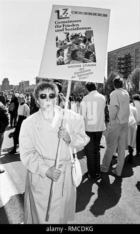 Mai 1, 1989: Tag der Arbeit und Urlaub der Arbeiterklasse. Mehrere hunderttausend Menschen an der VIP-stand der ehemaligen Reichsbank Gebäude in der Karl-Marx-Allee im Osten von Berlin. Poster und Banner sind zur Teilnahme an den Kommunalwahlen in der DDR am 7. Mai 1989 zu fördern. Der Opposition in der DDR zeigt massive Verfälschungen der Ergebnisse nach den Wahlen. Stockfoto