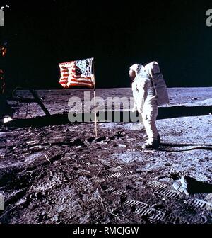 Edwin "Buzz" Aldrin, der zweite Mann auf dem Mond und Kommandant der Apollo 11 Mondlandefähre "Eagle", Wandern auf dem Mond vor der US-Flagge. Apollo 11 war die erste bemannte Mondlandung Mission, mit, dass die wichtigste Mission für die Menschheit. Stockfoto