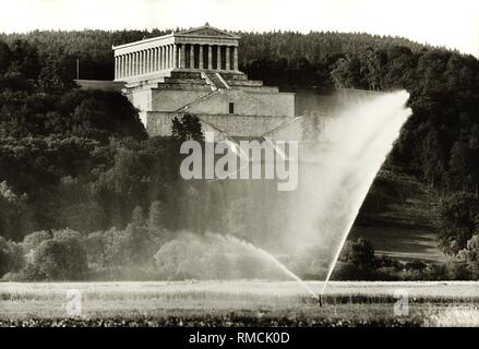 Blick auf die Walhalla, eingebettet in die Landschaft der Donau Tal in der Nähe von Donaustauf. Es wurde zwischen 1830 und 1842 im Auftrag von Ludwig I. von Bayern, der von Leo von Klenze nach dem Vorbild des Parthenon auf der Akropolis erbaut. Der Name Walhalla stammt aus dem Altnordischen Hall des Valholl. Die Walhalla ist eine der wichtigsten Sehenswürdigkeiten in Bayern. Im Vordergrund die Brunnen der Bewässerung der Felder. Stockfoto