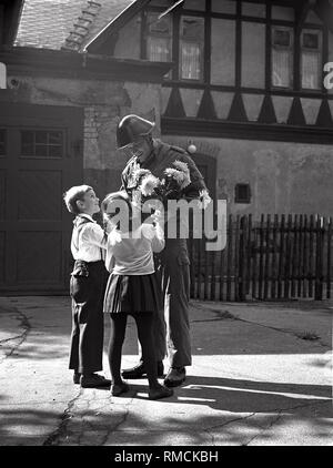 Zwei junge Pioniere präsentieren einen Blumenstrauß zu einem Offizier der Nationalen Volksarmee (NVA). Stockfoto