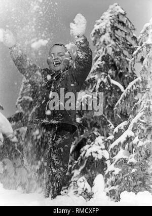 Mädchen wirft Schnee in die Luft, 50 s Stockfoto