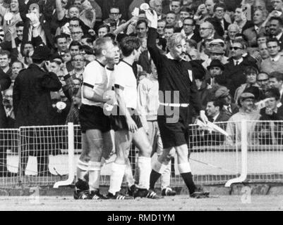 Der russische Linienrichter Tofiq Bahramov (rechts) erkennt England's drittes Ziel gegen Deutschland, die Deutschen Spieler beschweren. Stockfoto