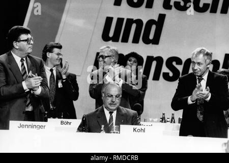 Die Delegierten und das Präsidium begrüßt Bundeskanzler Helmut Kohl für ungefähr drei Minuten nach seiner Rede zu Beginn der Bundesparteitag der CDU in Mainz. Von links: Bundestagspräsident Philipp Jenninger, Bundeskanzler Helmut Kohl, Generalsekretär Heiner Geisser. Hinter Jenninger der Bundesvorsitzende der Jungen Union Christoph Boehr und der rheinland-pfaelzische Ministerpraesident Bernhard Vogel. Stockfoto