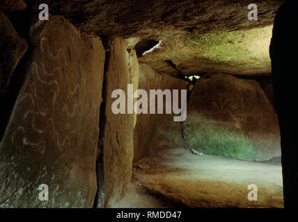 Megalithische Kunst inside Mané lud Neolithischen passage Grave, Morbihan, Bretagne, Frankreich. Gabeln auf eine Passage Stein & eine 'Figur' in der Grabkammer. Stockfoto