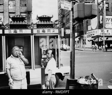 Männer asiatischer Abstammung, Anruf auf öffentliche Fernsprecher in New Yorks Chinatown. Die Beschriftung der Telefonzellen ist Chinesisch. Stockfoto