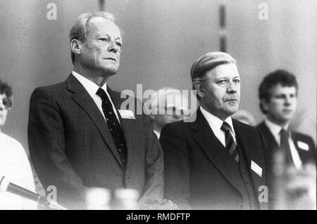 Vorsitzende Willi Brandt und Helmut Schmidt während einer Schweigeminute für die verstorbenen Mitglieder der Partei auf dem Parteitag der SPD in der Olympiahalle in München am 19. April 1982. Stockfoto