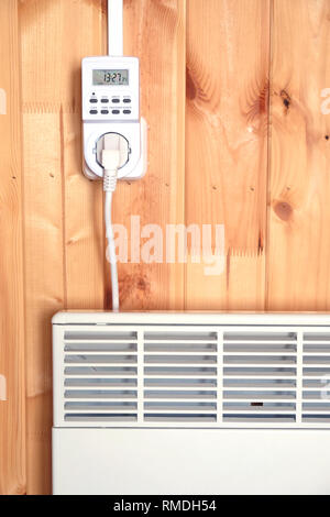 Arbeiten weiß elektrischer Konvektor Heizung angeschlossen, um timer Steckdose im Smart house System betrieben gegen die hölzerne Wand im Zimmer Frontansicht closeu Stockfoto