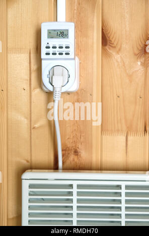 Arbeiten weiß elektrischer Konvektor Heizung angeschlossen, um timer Steckdose im Smart house System betrieben gegen die hölzerne Wand im Zimmer Frontansicht closeu Stockfoto