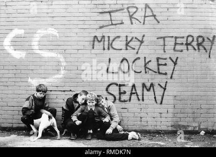 Kinder im 'Frieden', eine Wand, die durch Belfast läuft Katholiken und Protestanten voneinander zu trennen. Die Kinder sind hier auf der katholischen Seite. Stockfoto