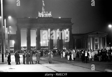 Blick von Osten Berlin zum Brandenburger Tor in der Nacht vom 9. auf den 10. November, nach dem "Fall der Mauer". Die Bürger von Ost und West Berlin stehen unter dem Tor und an der Wand (hinter), DDR-Grenztruppen sind vor und nach dem Tor. Stockfoto