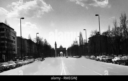 Blick auf die Leopoldstraße in München mit dem Siegestor und im Hintergrund der Turm der Ludwigskirche. Das Foto wurde retuschiert: Autos auf der Straße wurden entfernt und parken die Autos wurden an den rechten Rand des Bildes hinzugefügt. (Undatiertes Foto). Stockfoto