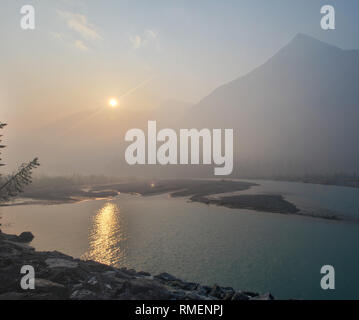 Wald Feuer Rauch in Kootenay National Park, British Columbia, macht einen schönen Sonnenaufgang, auf der Kootenay River nieder. Stockfoto