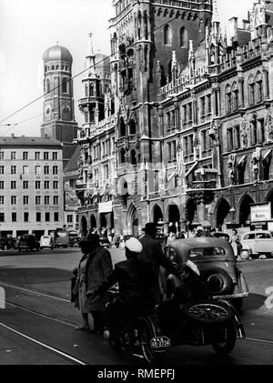 Die Neue Rathaus (Neues Rathaus) in München. Vor ein Motorrad, Autos und Fußgänger und im Hintergrund die Türme der Frauenkirche (Kathedrale Unserer Lieben Frau) (Undatiertes Foto). Stockfoto