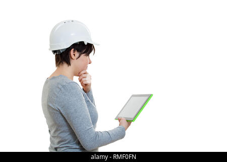 Seitenansicht nachdenklich der jungen Frau Ingenieur tragen Schutzhelm mit einem Tablet Computer Gadget auf weißem Hintergrund berechnen. Stockfoto