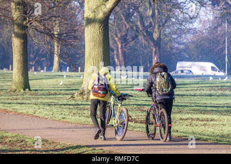 Northampton. Großbritannien 15. Februar 2019. Wetter. Eine helle, sonnige, frostig-kalten Morgen. Zwei Jungs schieben Sie ihre Räder durch die Allee der Bäume in Abington Park auf dem Weg zur Schule. Credit: Keith J Smith./Alamy leben Nachrichten Stockfoto