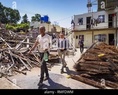 Sihanoukville, Preah Sihanouk, Kambodscha. 15 Feb, 2019. Chinesische Bauarbeiter in Sihanoukville Spaziergang durch ihr Wohngebiet auf dem Weg zum Mittagessen. Die Arbeiter leben in prefabbed Einheiten in China hergestellt und übereinander wie Container gestapelt. Es gibt etwa 80 Chinesische Kasinos und Hotels in Sihanoukville und Dutzende weitere sind im Bau. Die Casinos sind die Änderung der Stadt, die einst ein verschlafenes Port auf Südostasien'' backpacker Trail'' in eine boomende Stadt. Die Änderung ist mit einer Kosten zwar. Viele kambodschanische Bewohner von Sihanoukville haben ihre Häuser verloren Stockfoto