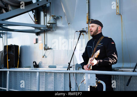 15. Februar 2019, Niedersachsen, Wilhelmshaven: Ein Marine der Fregatte Augsburg steht auf dem Schiff während seiner Rückkehr, Singen und Gitarre spielen. Foto: mohssen Assanimoghaddam/dpa Stockfoto