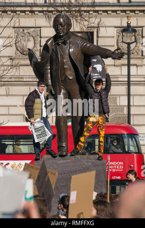 Parliament Square, London, UK. 15. Februar, 2019. Tausende Studenten verlassen die Klassen der Regierung zu protestieren, die dringende Maßnahmen zur Bekämpfung des Klimawandels bei Jugend Streik 4 Klima Demo zu nehmen, sich versammeln in der Westminster Parliament Square in der Frühlingssonne. Die Studierenden des David Lloyd George Statue mit Plakate. Credit: Malcolm Park/Alamy Leben Nachrichten. Stockfoto