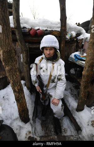 Januar 17, 2019 - Donezk, Donezk Volksrepublik (DPR) D, Ukraine-DPR Soldat, hiess, Sergej, der zweite das Kommando über die Division Shakhtyorsk gesehen, die sich aus einem Graben foxhole bewaffnet mit seinem kalaschnikow. Der Krieg zwischen der ukrainischen Armee und die Soldaten der Donezk Volksrepublik hat das Leben von 12.000 Menschen und diejenigen, die vertrieben wurden mehr als eine Million. Das im Jahr 2014 eskaliert. Trotz eines Waffenstillstandes im Ort, es ist offensichtlich, dass der Tod immer noch Auftritt von vorwiegend, Sniper, Mörtel und Minen. den Bau von Schützengräben auf beiden Seiten von Niemandsland, (oft nur 100 Stockfoto