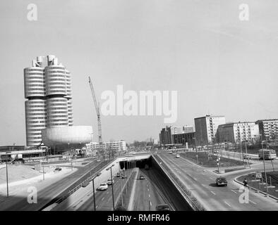 Die nördlichen Mittleren Ring in den letzten Ausbauarbeiten. Die petuelring im Norden von München wurde in den frühen 1970er Jahren im Zuge der Olympischen Spiele erweitert. Im Hintergrund ist das neue Merkmal BMW-Vierzylinder (BMW 4-Zylinder), in dem die Hauptverwaltung des Herstellers liegt. Der Kran Punkte wahrscheinlich die letzten Arbeiten auf dem Bau, der im Frühjahr 1973 eingeweiht wurde. Stockfoto