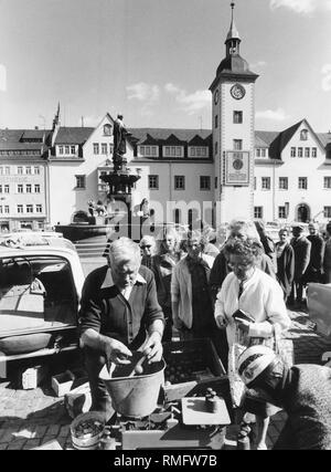 Undatiertes Bild der Markt vor dem Rathaus von Freiberg. Aufgrund der schlechten Versorgungslage für Obst und tropische Früchte, eine lange Schlange gebildet hat. Auf dem Rathausturm, die DDR ist zu gratulieren, ihr 25-jähriges Jubiläum" für den Sozialismus, Frieden und Wohlstand". Stockfoto