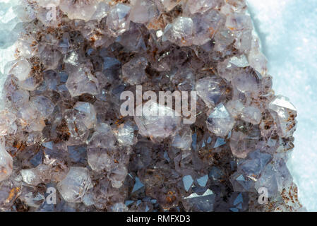 Amethyst natürliche crystal Cluster mit Goethit Einschlüsse aus Brasilien auf weißem Schnee an einem sonnigen Wintertag. Stockfoto