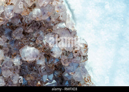 Amethyst natürliche crystal Cluster mit Goethit Einschlüsse aus Brasilien auf weißem Schnee an einem sonnigen Wintertag. Stockfoto