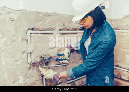 Nahaufnahme der weiblichen Klempner in Handschuhe mit Drehmomentschlüssel Reparaturen die Rohre im Bad. Reparatur von Rohrleitungen, Ventile, Wasser m. Stockfoto