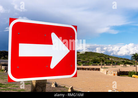 Ein roter Pfeil an der Küste Parkplatz auf dem Weg zum Strand. Stürmische Wolken im Hintergrund. Kapstadt, Südafrika. Stockfoto