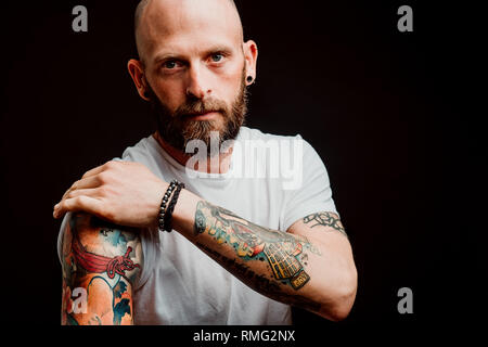 Unbehaarte Hipster in t-shirt, bärtigen Tattoos auf Händen auf schwarzem Hintergrund Stockfoto