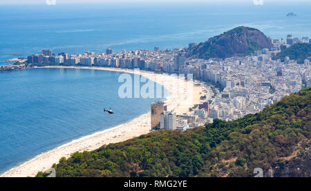 Majestic drone Ansicht von weit entfernten Hubschrauber fliegen über Sandstrand und moderne Küstenstadt in Brasilien Stockfoto