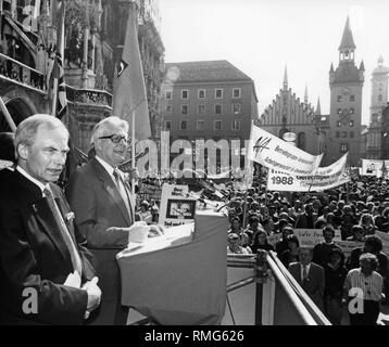 Der SPD-Vorsitzende Hans-Jochen Vogel hält eine Rede vor einer Masse von Zuschauern am Marienplatz in München am Tag der Arbeit. Auf der linken Seite neben ihn, sein Nachfolger, Bürgermeister von München Georg Kronawitter. Hinter der Fassade des Rathauses. Stockfoto